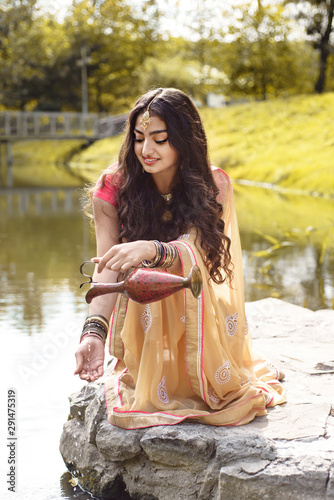 Indian girl pours water from the jug to her hand