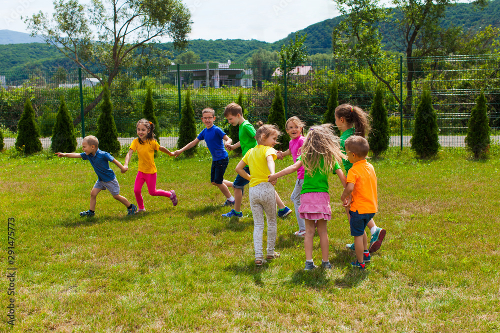 Obraz premium Children play outdoors. Train game - kids holding hands like