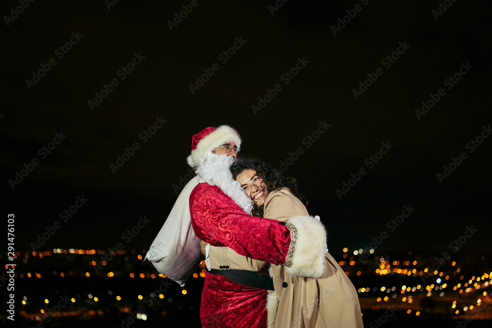happy young woman hugging santa claus at night