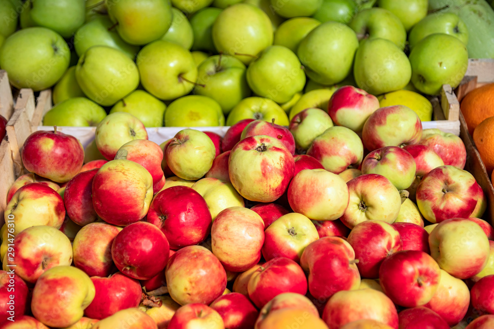 Red and green ripe apples in boxes close-up on the market