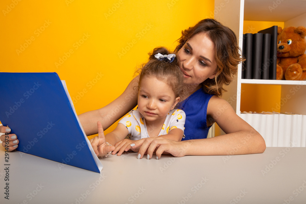 Mother and daughter reading sitting at home at the table Mother and daughter reading sitting at home at the table