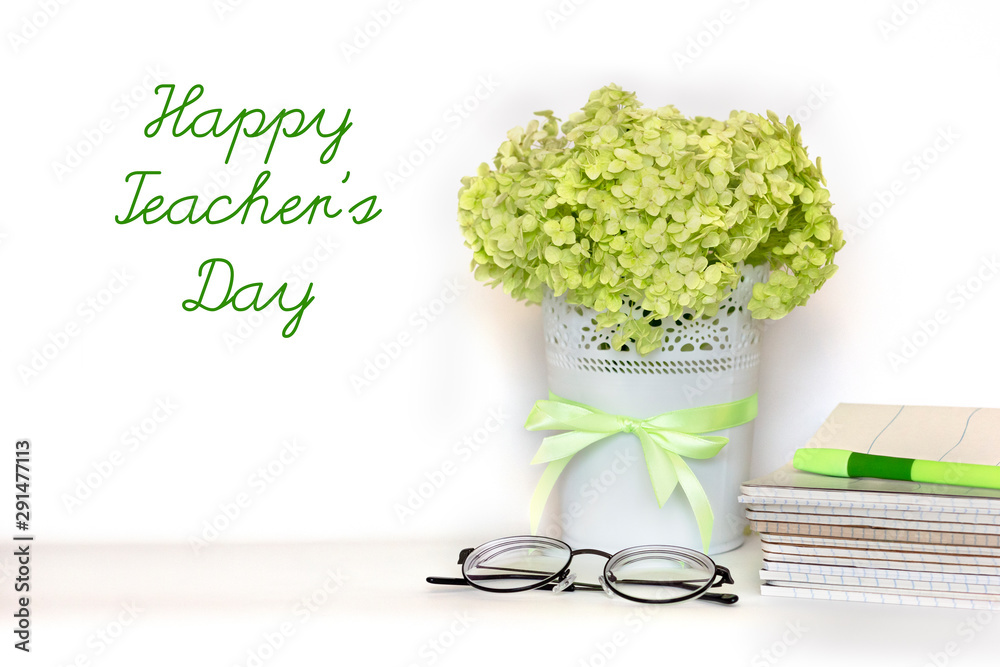 Happy Teacher's day greeting card - bouquet of light green hydrangea branch  in flower pot with satin ribbon, pile of notebooks, glasses and pen on  white background. International school Teacher Day. Stock