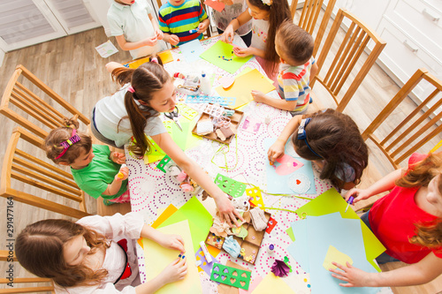 Group of children around the table making postcards together
