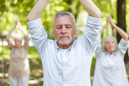 Serene mature man doing qigong exercise in the park photo