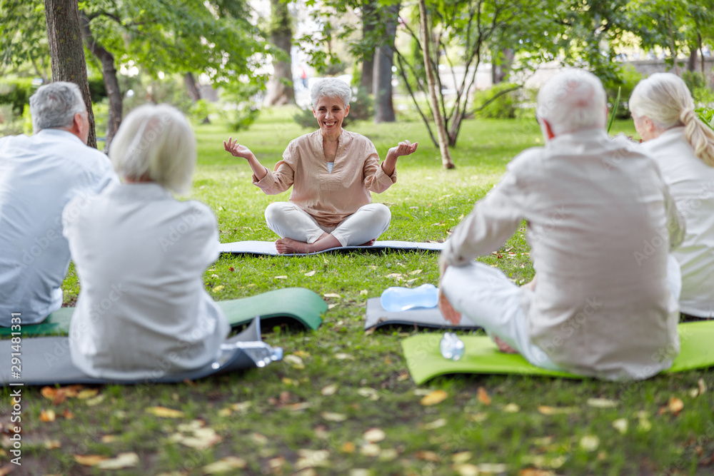 Cheerful senior lady teaching yoga class in the park Cheerful senior lady teaching yoga class in the park