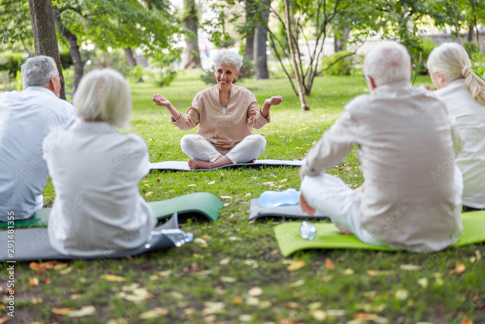 Smiling senior lady teaching yoga class in the park Smiling senior lady teaching yoga class in the park