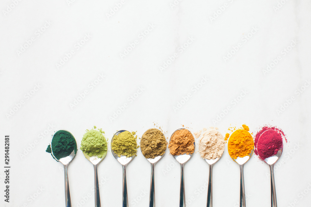 Kitchenware with different colorful superfood powders on wooden table Kitchenware with different colorful superfood powders on wooden table