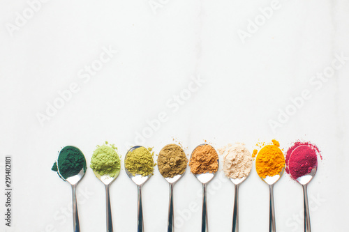 Kitchenware with different colorful superfood powders on wooden table photo