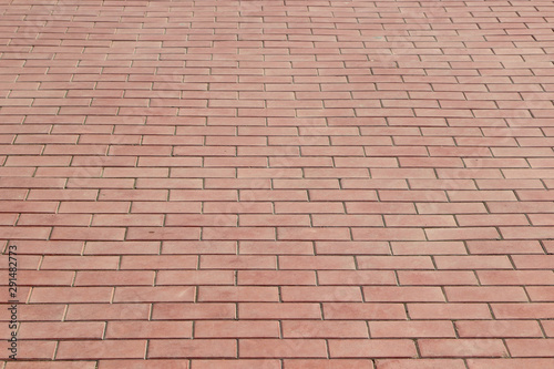 Sidewalk paved with rectangular red tiles in perspective