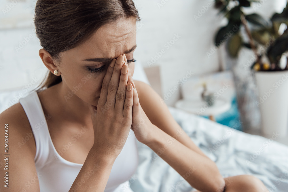 stressed young woman sitting on bed and showing please getsure stressed young woman sitting on bed and showing please getsure