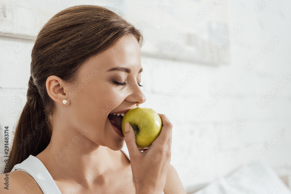 attractive young woman eating green apple in bed attractive young woman eating green apple in bed