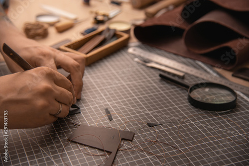 Working process in the leather workshop. Man's hands holding crafting tool