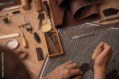Working process in the leather workshop. Man's hands holding crafting tool photo