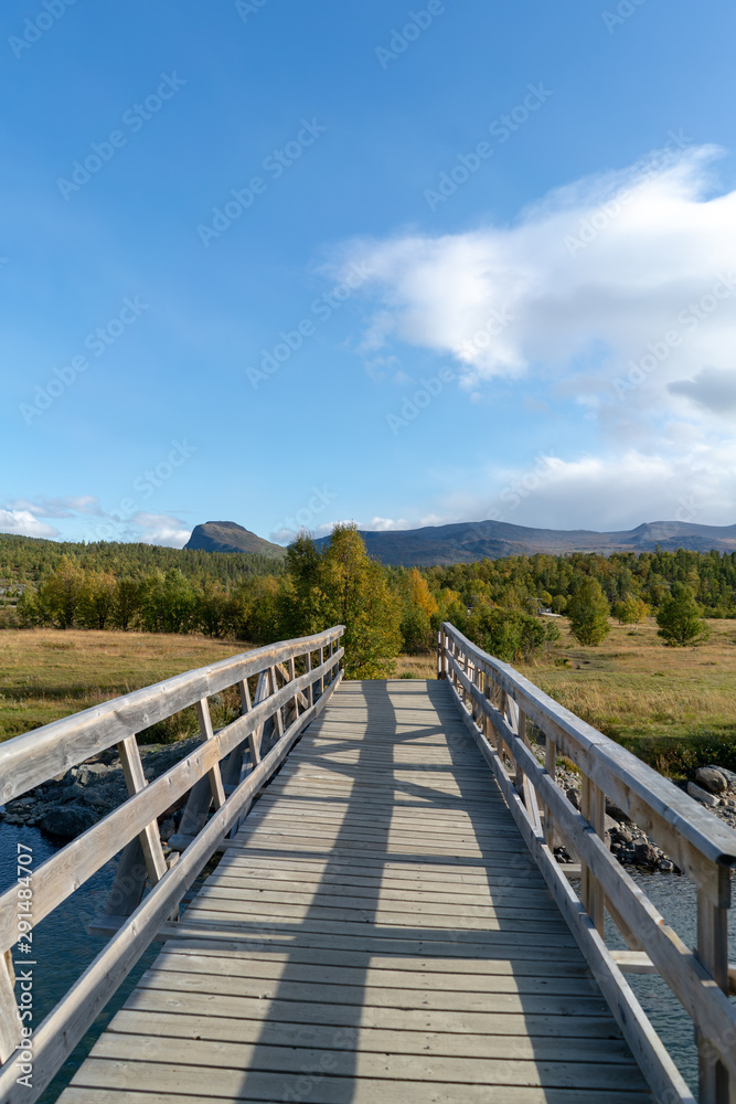 Holzbrücke in Norwegen im Herbst mit Fluss und Wolken