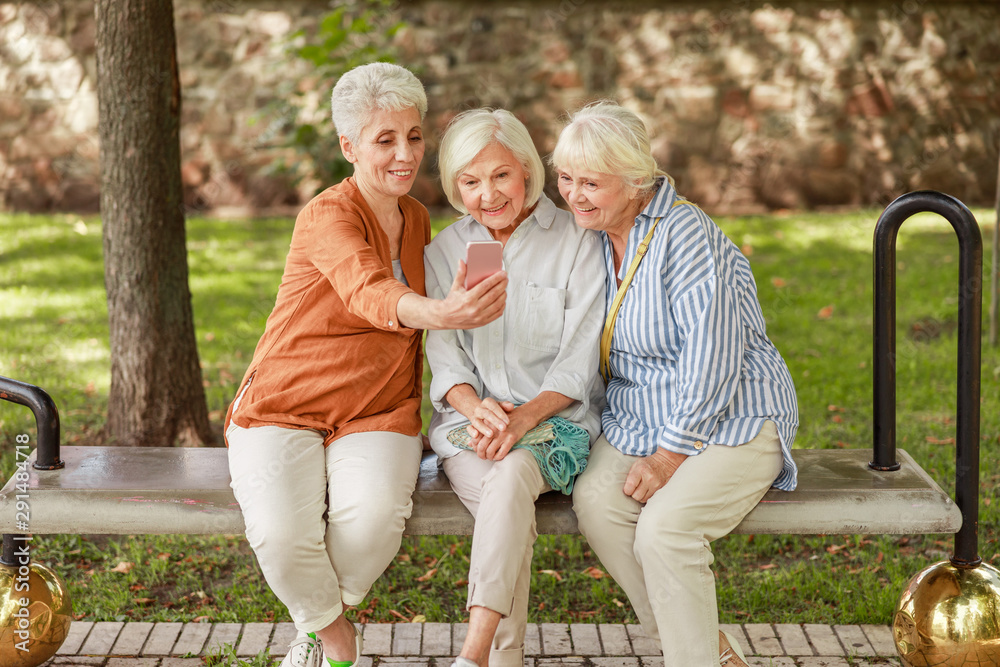 Fototapeta premium Cheerful old women making selfie on the street