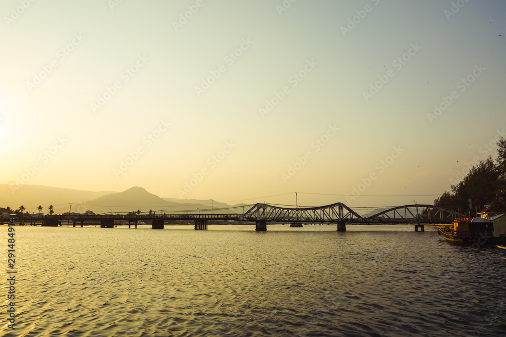 Old French bridge across Praek Tuek Chhu River in Kampot Province, Cambodia. Scenic sunset over Kampot.