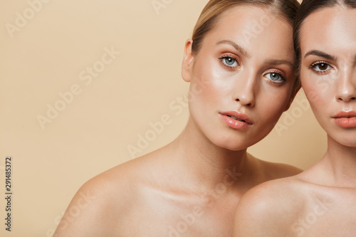 Women posing naked isolated over beige wall background.