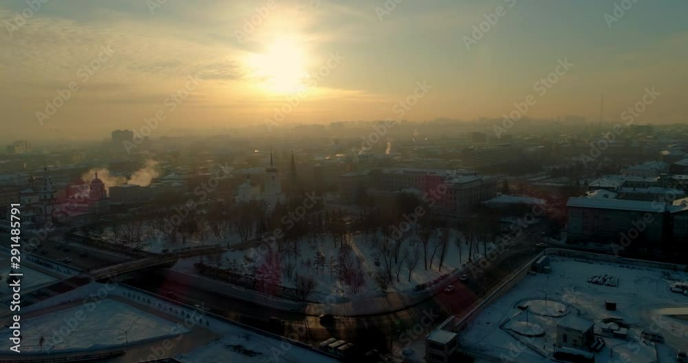 Aerial: Vehicles on street in snow covered city against orange sky - Irkutsk, Russia Aerial: Vehicles on street in snow covered city against orange sky - Irkutsk, Russia