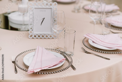 White plate and plate with metal beads. Pink cloth napkin on a dinner plate and cutlery
