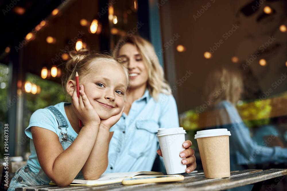 Cute smiling girl in cafe with her mum stock photo