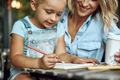 Little girl drawing and her mother smiling stock photo