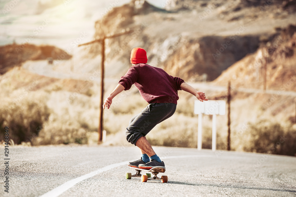 © cppzone - Hipster rides on long board by mountain road © cppzone - Hipster rides on long board by mountain road