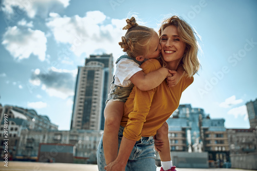 Cute girl kissing cheek of her mother stock photo