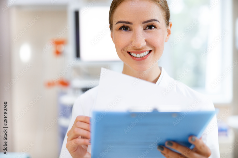 Happy young physician with clipboard in office stock photo Happy young physician with clipboard in office stock photo