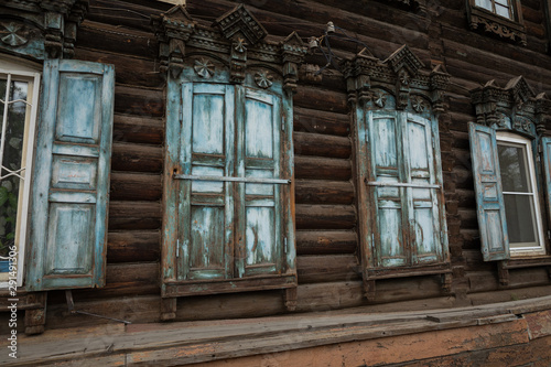 Window with the wooden carved architrave in the old wooden house in the old Russian town. Irkutsk