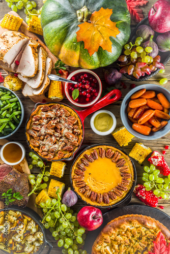 Thanksgiving family dinner setting concept. Traditional Thanksgiving day food with turkey, green beans and mashed potatoes, stuffing, pumpkin, apple and pecan pies, rustic wooden table