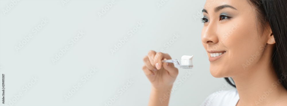 Beautiful Asian woman with toothbrush and paste on light background Beautiful Asian woman with toothbrush and paste on light background