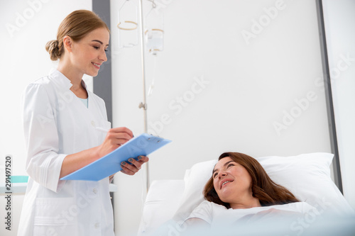 Smiling adult woman is looking at her doctor