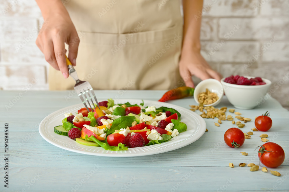 Woman eating tasty salad at table, closeup Woman eating tasty salad at table, closeup