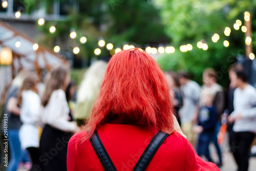 Girl with bright red hair on the street. Beautiful street with lights. Youth.