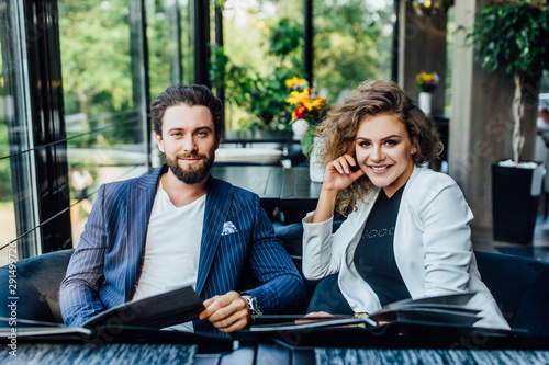 Gorgeous young and pretty couple with menu in a restaurant making order, happy dating.  Looking to the camera. © Тарас Нагирняк