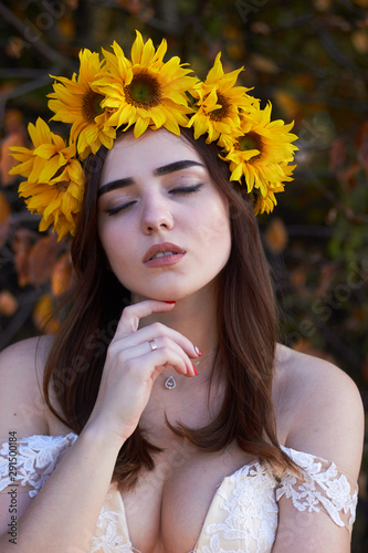 Fotografie Portrait of a beautiful young girl with a wreath of sunflowers on her head