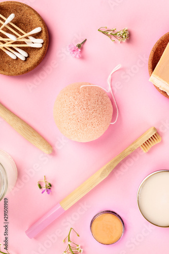 Plastic-free, zero waste cosmetics, flat lay pattern on a pink background. Bamboo toothbrushes and cotton swabs, konjac sponge, etc, shot from the top