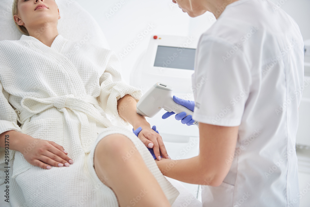 Young lady receiving laser hair removal treatment in modern beauty salon Young lady receiving laser hair removal treatment in modern beauty salon