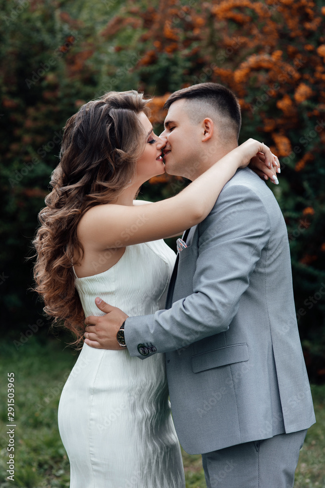 Fototapeta premium Young couple in love outdoor. Young couple in celebrate outfits among the branches of sea buckthorn. A loving couple, a guy and a girl kiss and hug. Happy lovers and family. Love story. 