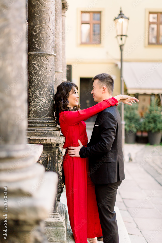 young beautiful Chinese couple in love hugging each other on old city street, summer Europe vacation, travel, fun, happy, smiling, date, embracing