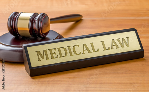 A gavel and a name plate with the engraving Medical law