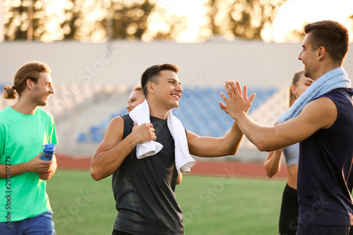 Sporty young men giving each other high-five at the stadium