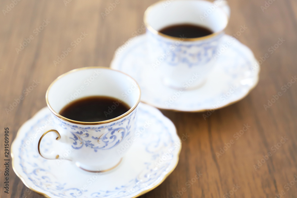 白い壁の背景に木製テーブル。その上に置かれたコーヒーカップ 白い壁の背景に木製テーブル。その上に置かれたコーヒーカップ