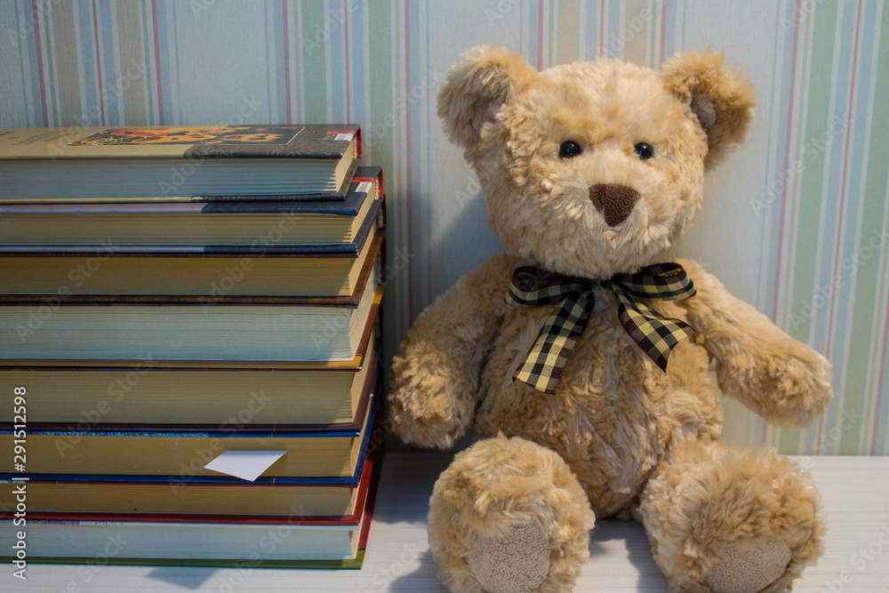 A stack of books and a plush bear on a white table A stack of books and a plush bear on a white table