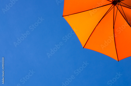 Orange umbrella / parasol viewed from below against a blue sky