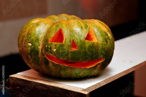 Halloween oblate pumpkin head. Orange pumpkin with a smile and eyes on wooden background.