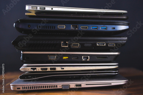 Stack of old laptops with dark background. Side