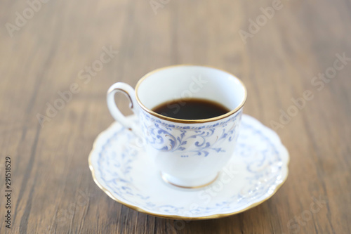 木製テーブルの上に乗った白い陶器のカップ&ソーサーにブラックコーヒー © task