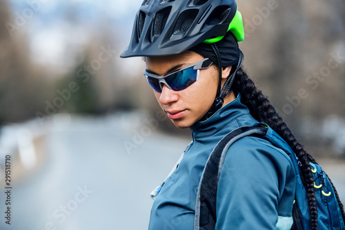 Female mountain biker standing on road outdoors in winter.