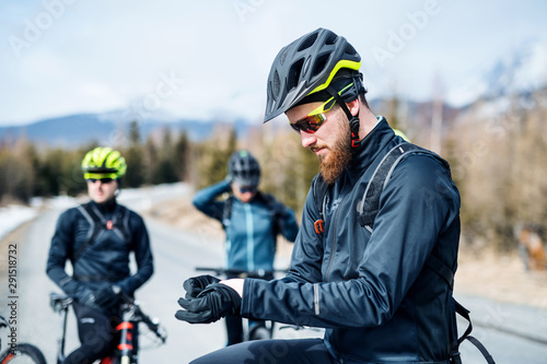 Group of mountain bikers standing on road outdoors in winter.